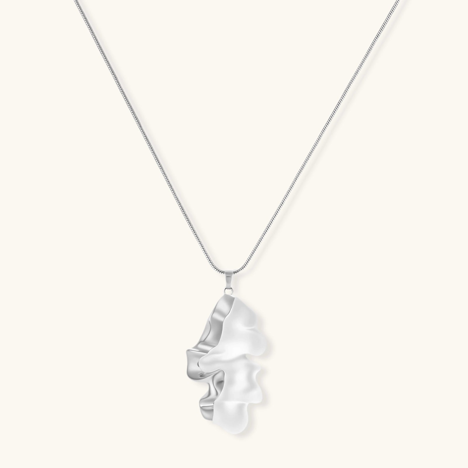 Close-up of a sculptural necklace with flowing wave pendant made from eco-zinc alloy on adjustable chain