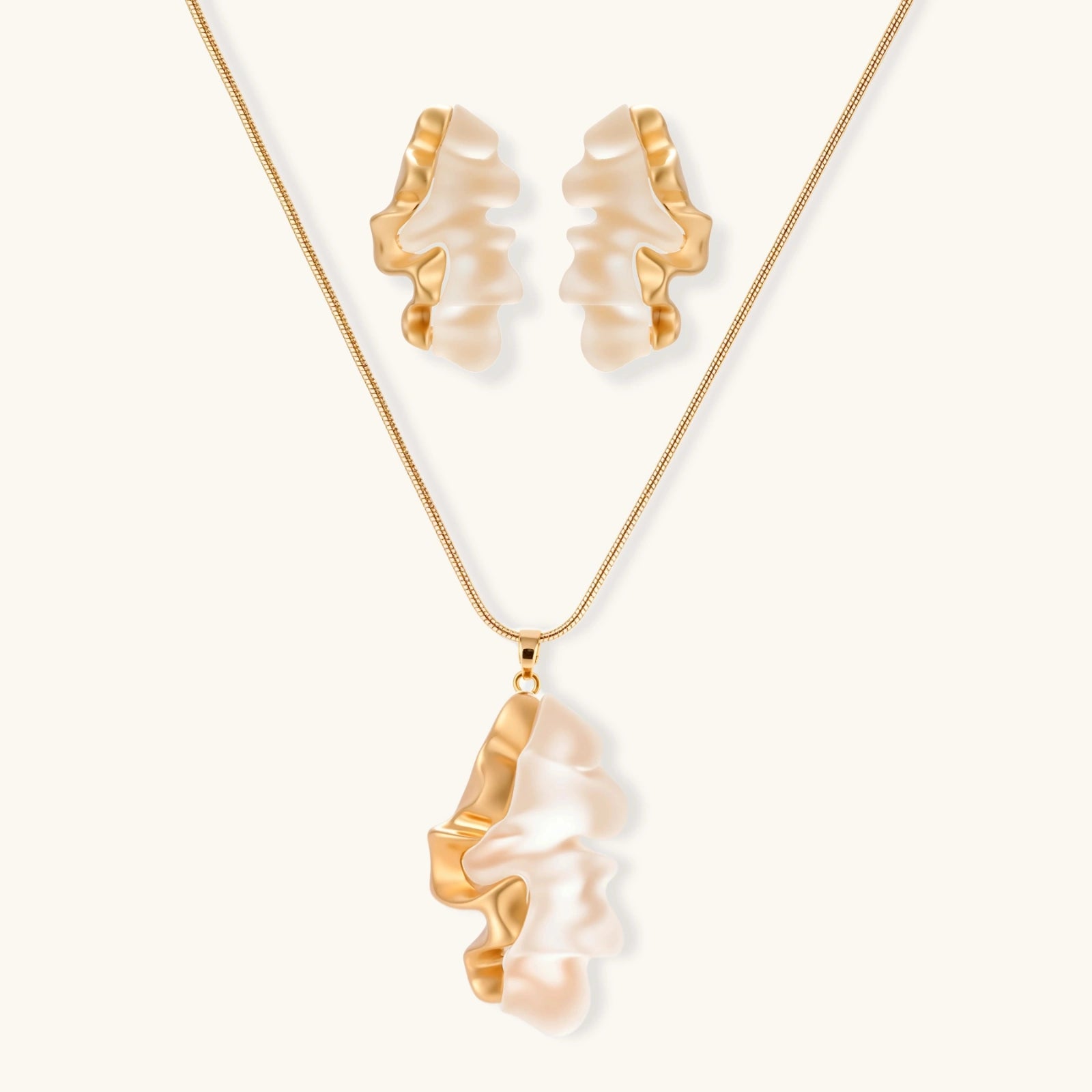 Sculptural gold-toned jewelry set featuring wavy organic earrings and matching necklace pendant with translucent resin accents.